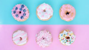 ピンクとブルーのテーブルに並べられたデコレーションドーナツ6個のある風景